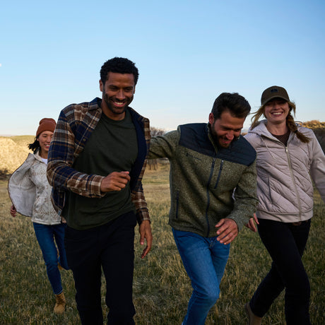 Four people walking together in a field on a sunny day