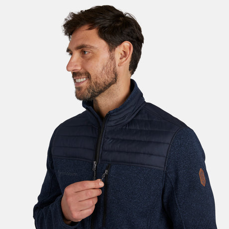 A man with brown hair and a beard smiles while zipping up the Free Country Men's Frore Knit Fleece Jacket, featuring quilted shoulders and a convertible collar, against a plain white background.