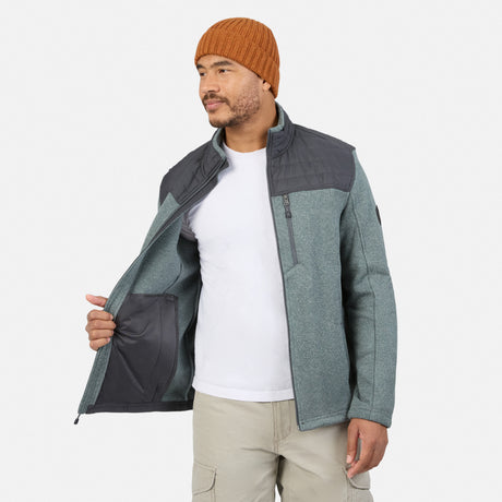 A person wearing a Men’s Frore Knit Fleece Jacket in gray with a charcoal shoulder panel, zippered chest pocket, and convertible collar, shown partially open to reveal the interior.