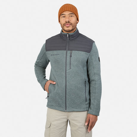 A man wearing an orange beanie and a Thyme-colored Free Country Men’s Frore Knit Fleece Jacket featuring a dark gray panel on the chest and shoulders.