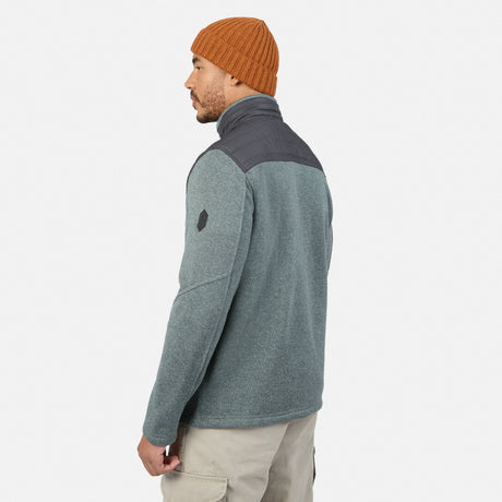 A man wears a grey Men’s Frore Knit Fleece Jacket with a charcoal upper panel and a brown knit beanie.
