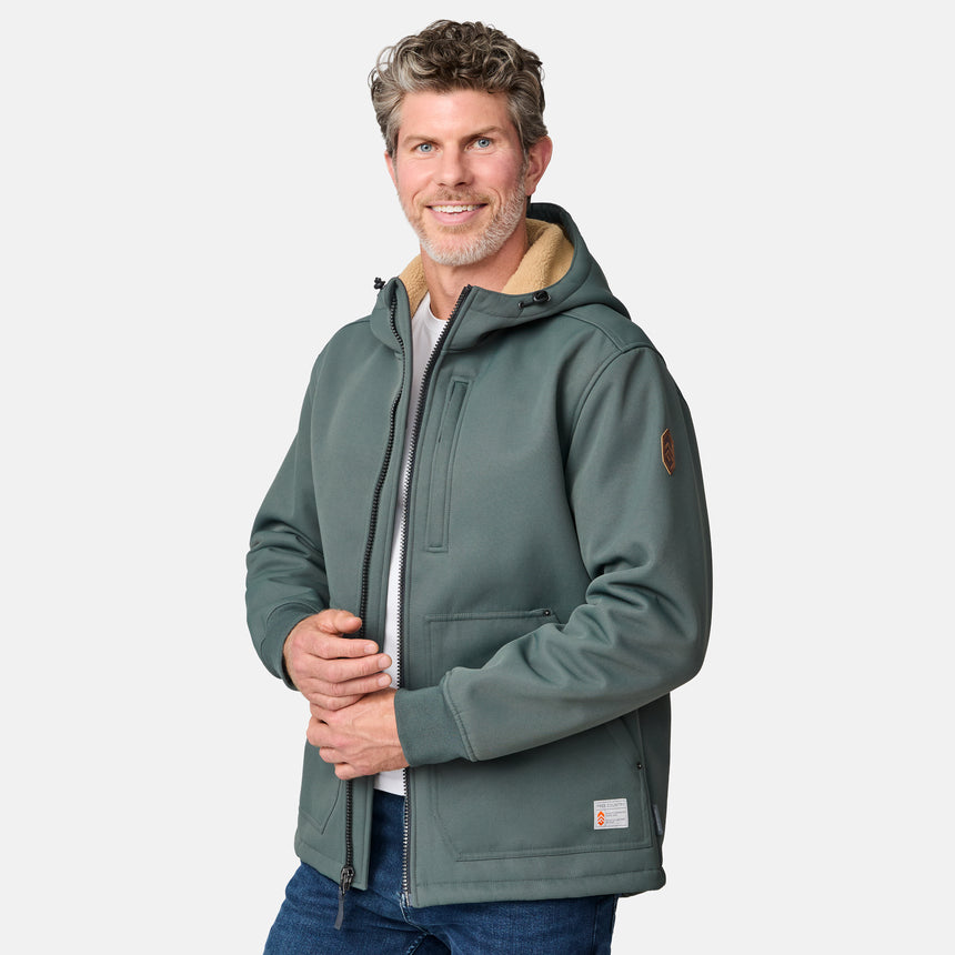 [Kolby is 6'2" wearing size M.] Men’s Free Country green hooded jacket featuring full front zipper, two side pockets, and zippered chest pocket. Includes utility patch on left sleeve and subtle brand label at lower hem. Styled with blue jeans for a laid-back cold-weather look highlighting functional design and casual edge.
