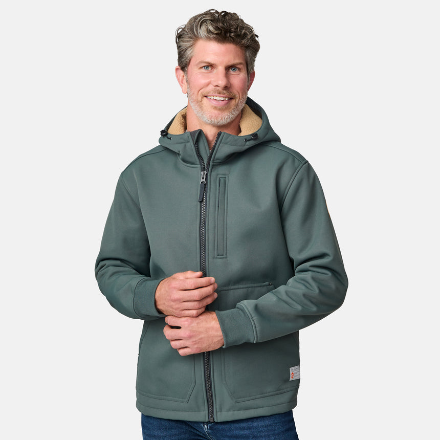 [Kolby is 6'2" wearing size M.] Men’s Free Country green hooded jacket featuring full front zipper, two side pockets, and zippered chest pocket. Includes utility patch on left sleeve and subtle brand label at lower hem. Styled with blue jeans for a laid-back cold-weather look highlighting functional design and casual edge.