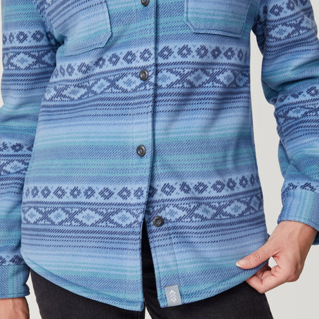 [Model is wearing size S.] A close-up of a person wearing a blue patterned button-up shirt with Fair Isle style geometric stripes in shades of blue and navy. The shirt has a textured knit appearance, button closure, and chest pockets, shown against a light gray background.