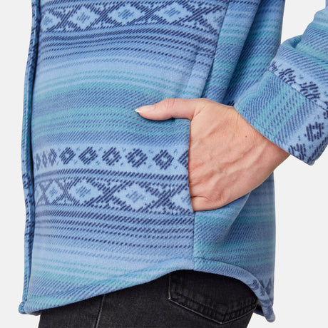 [Model is wearing size S.] Close-up of a person wearing a blue patterned knit top with a side pocket, with their hand in the pocket. The top features horizontal stripes and geometric Fair Isle-style patterns in shades of blue, teal, and navy.