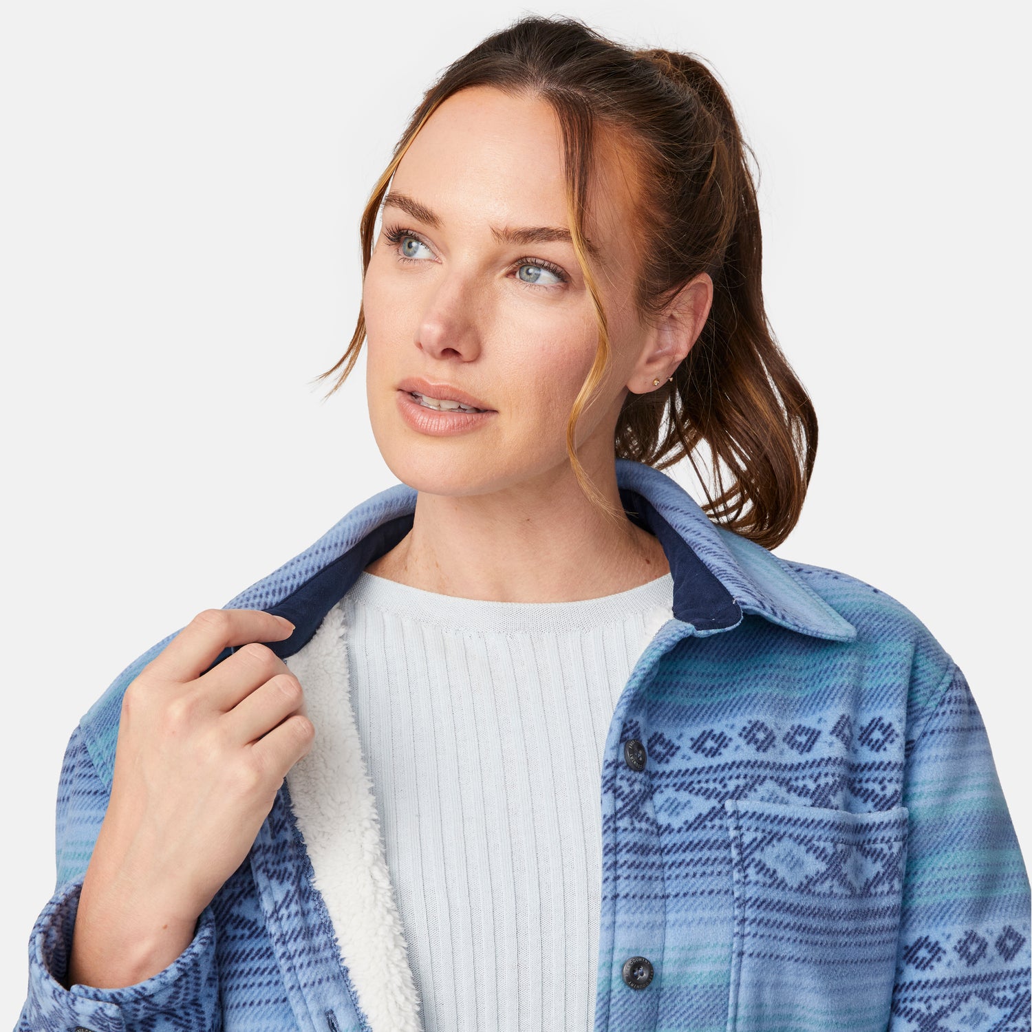 [Model is wearing size S.] Close up of a woman wearing a blue patterned button-up shirt jacket over a white ribbed top and black jeans, photographed against a light gray studio background.