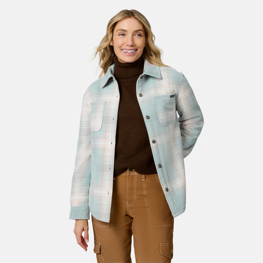 [Model is wearing size S.] A woman modeling a light blue and white plaid button-up overshirt over a dark brown turtleneck sweater and brown cargo pants, set against a plain light gray studio background.