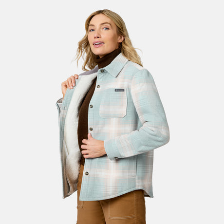 [Model is wearing size S.] A woman modeling a light blue and white plaid button-up flannel shirt jacket with a soft fleece lining, worn over a brown turtleneck and tan pants against a light gray background.