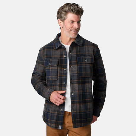 [Kolby is 6'2" wearing size M.] Men’s Free Country plaid button-down shirt in blue and brown checkered pattern, featuring dual chest pockets with button flaps and a relaxed fit. Paired with brown pants for a casual fall-ready look, ideal for outdoor layering.