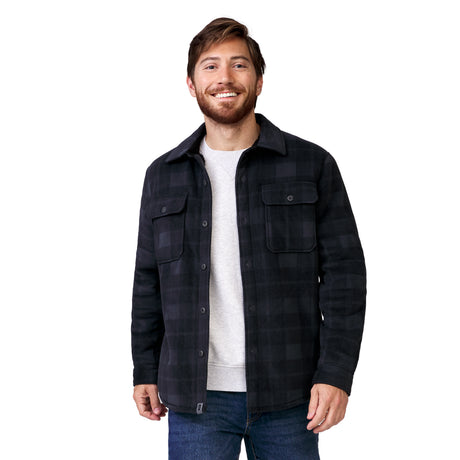 A smiling man wearing a dark gray plaid Free Country Men’s Chill Out Fleece Shirt Jacket over a light gray crew-neck shirt and blue jeans.
