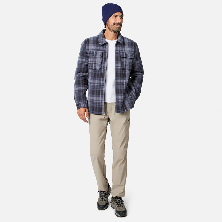 [Model is wearing size M.] A man wearing a navy and gray plaid button-up shirt jacket over a white t-shirt, khaki pants, and a navy beanie, standing against a light gray studio background.