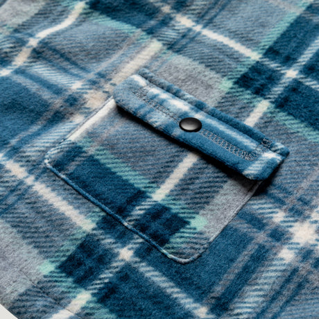 Close-up of the Chill Out Fleece Sherpa Lined Dog Jacket by Clearance, featuring blue and gray plaid flannel with a buttoned chest pocket and soft, textured fabric—ideal for cozy comfort in your pup's reversible outerwear.