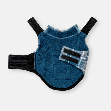 The Clearance Chill Out Fleece Sherpa Lined Dog Jacket is a blue jacket with black and plaid details, adjustable Velcro straps, and a soft sherpa lining, shown laid flat on a white background.