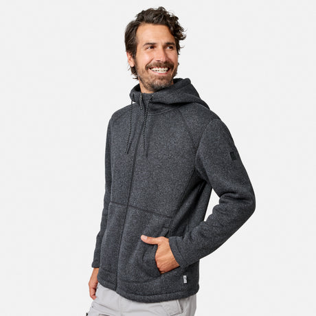 [Model is wearing size M.] A man wearing a dark gray Free Country Men’s Mountain Fleece Jacket with his left hand in the pocket, standing and smiling while looking to his left against a plain light background.