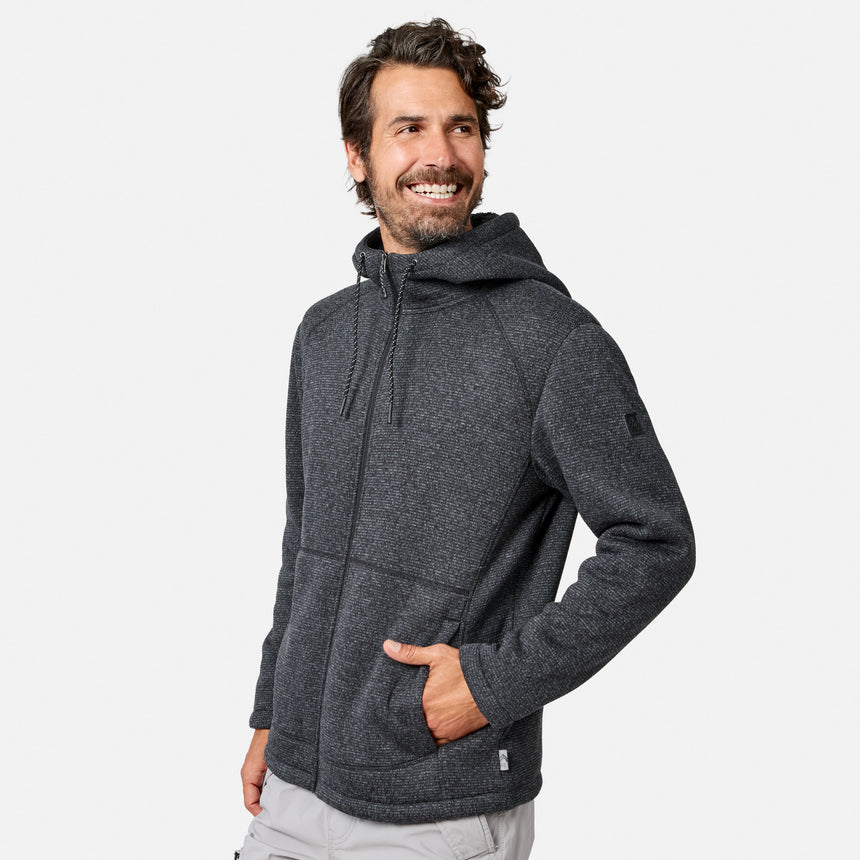 [Model is wearing size M.] A man wearing a dark gray Free Country Men’s Mountain Fleece Jacket with his left hand in the pocket, standing and smiling while looking to his left against a plain light background.