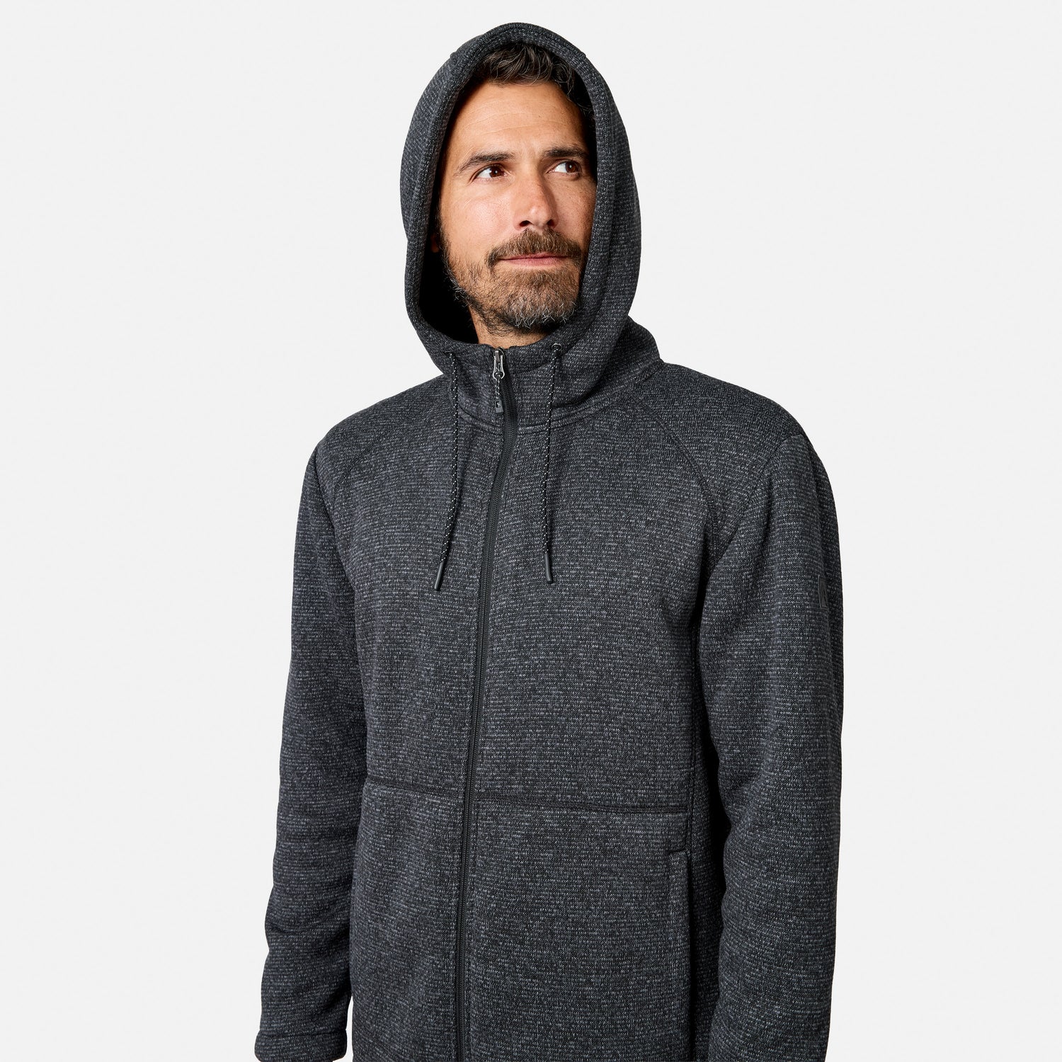 [Model is wearing size M.] A bearded man wearing a dark gray Men’s Mountain Fleece Jacket by Free Country with a zip-up hood looks slightly to the side against a plain white background.
