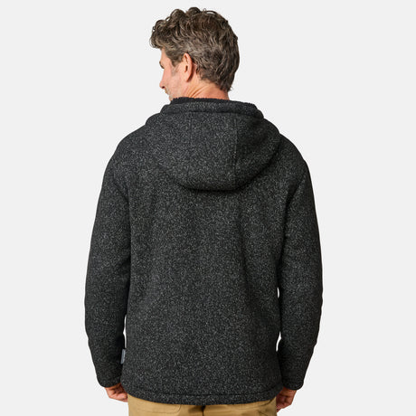 [Kolby is 6’2” wearing a size Medium.] Man wearing the Free Country Men's Northwood Mountain Fleece Hoodie in heather black with black drawstrings, standing with hands in pockets against a plain, light background.