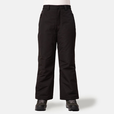 A person wears Free Country Kids' Padded Ski Pant—water-resistant black snow pants with straight legs, front pockets, built-in snow gaiters—plus black and gray winter boots and a white ribbed top, all against a white background.