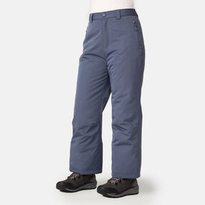 A child wearing Free Country Kids' Padded Ski Pant featuring snow gaiters, zippered pockets, and water resistance, paired with black winter boots against a plain light background. Ideal for cold weather activities.