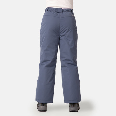 A child models the Free Country Kids' Padded Ski Pant in blue-gray, featuring water resistance and snow gaiters, paired with black boots. Only their lower half is visible as they stand facing away against a plain white background.