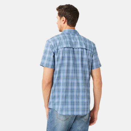 A man faces away, wearing the Free Country Men's Excursion Short Sleeve Poplin Shirt in light blue and white plaid with blue jeans, set against a plain white background.