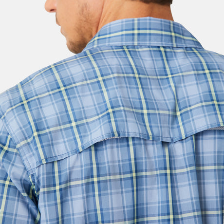 A close-up of a person wearing the Free Country Men's Excursion Short Sleeve Poplin Shirt, shown from the back and slightly angled, highlights the blue plaid shoulder and yoke details with moisture-wicking fabric for quick-dry comfort.