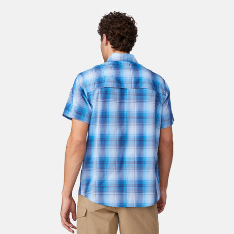 [Miguel is 6'2" wearing a size Medium.] in Blue Shadow Plaid, size M, made from lightweight moisture wicking polyester fabric featuring vent at the back, full button down front, and a stand collar, styled with khaki shorts #color_blue-shadow-plaid