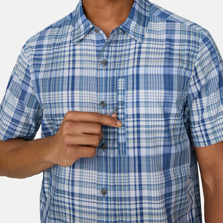 [Josiah is 6'3" wearing a size Medium.] Man wearing the Free Country Men's Excursion Short Sleeve Poplin Shirt in Denim Plaid, size M, made from lightweight moisture wicking polyester fabric featuring vent at the back, full button down front, and a stand collar, styled with navy shorts #color_ denim-plaid