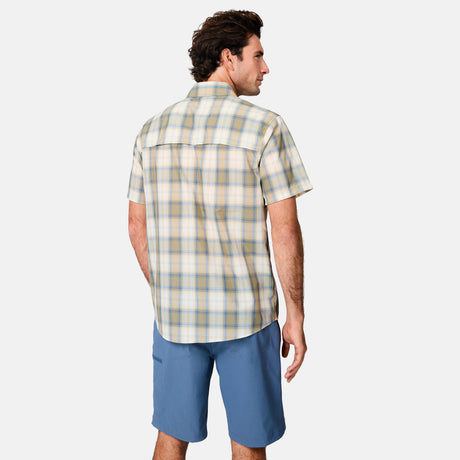 A man faces away, wearing the Free Country Men's Excursion Short Sleeve Poplin Shirt with moisture-wicking fabric and blue shorts against a plain light background.
