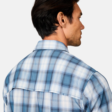 A man with dark hair is seen from behind, showcasing the Free Country Men's Excursion Short Sleeve Poplin Shirt in light blue and white plaid against a plain, light background that highlights his upper back and side profile.
