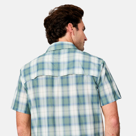 A man with wavy brown hair is seen from behind, wearing the Free Country Men's Excursion Short Sleeve Poplin Shirt in light blue and green plaid with moisture-wicking fabric, set against a plain gray background.