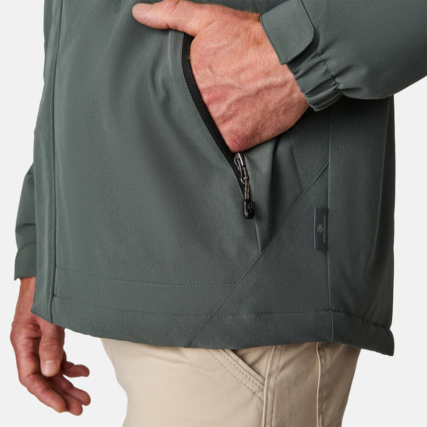 [Kolby is 6’2” wearing size M.]  "Men’s Free Country dark gray zip-front jacket with hood and chest pocket—layered over blue shirt and beige pants for a casual, transitional-weather look.