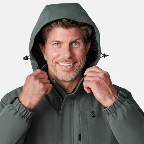 [Kolby is 6’2” wearing size M.]  "Men’s Free Country dark gray zip-front jacket with hood and chest pocket—layered over blue shirt and beige pants for a casual, transitional-weather look.