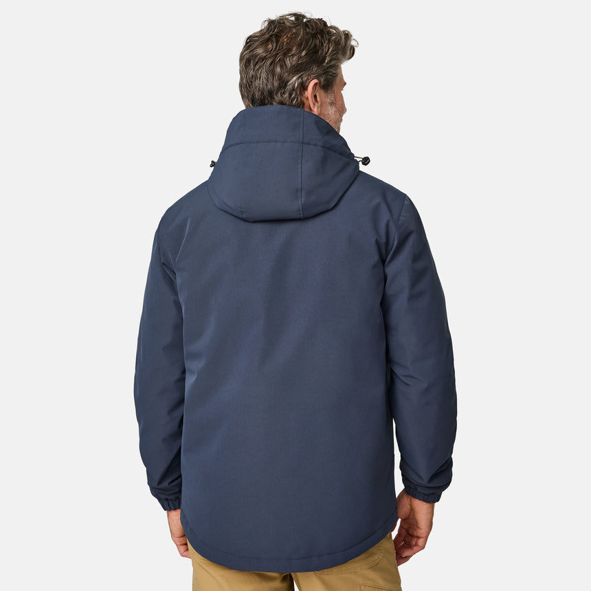 [Kolby is 6’2” wearing size M.] Men’s Free Country navy zip-front jacket with hood and high collar, featuring vertical chest zipper pocket and side hand pockets—worn over light brown pants for an outdoors-ready, insulated look.