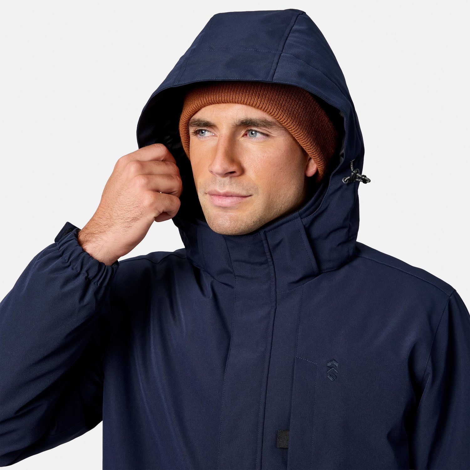 Rear view of a man in a navy Denali insulated jacket with the hood up and a rust beanie.