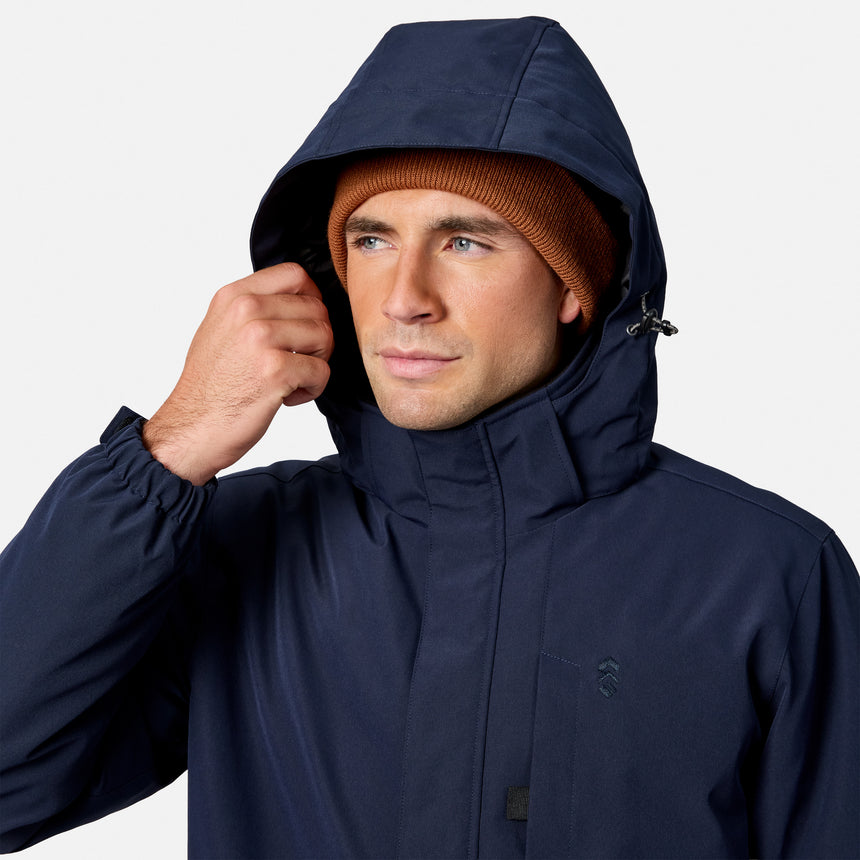 Rear view of a man in a navy Denali insulated jacket with the hood up and a rust beanie.