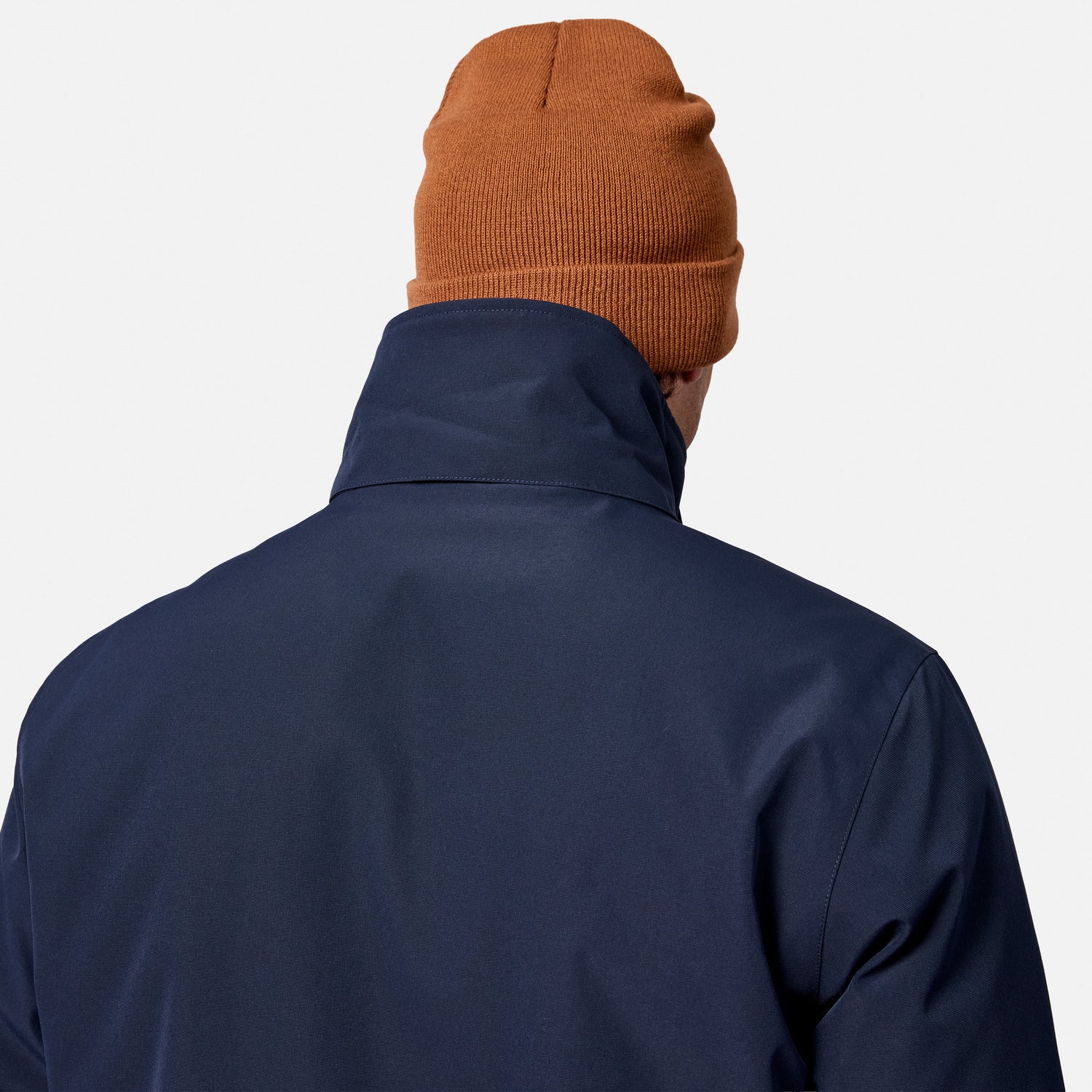 [Model is wearing size M.] Back view of a person wearing a navy blue jacket and an orange-brown knit beanie against a light gray background.