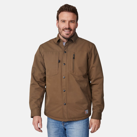 [Joe is 6'0" wearing size M.] Men’s Free Country brown canvas jacket layered over a white crewneck tee and blue jeans—features zippered chest pockets and left-side logo patch for rugged outdoor appeal and everyday versatility.