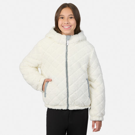 A young girl wearing a cream-colored, quilted sherpa jacket with a high collar and silver zipper, paired with black pants, against a light gray background.