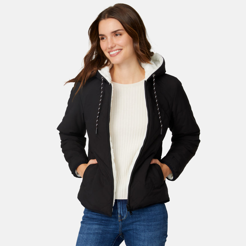 [Jessica is 5'9.5" wearing size S.] Free Country women’s black reversible quilted jacket with hood and patterned drawstrings, featuring zip-front closure and dual side pockets—styled with blue jeans for versatile, cold-weather wear.