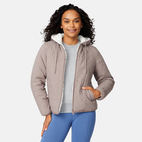 [Angelique is 5'10" wearing size S.] Light brown quilted reversible jacket with fleece-lined hood, zip front, and pockets; worn over grey shirt and blue pants.