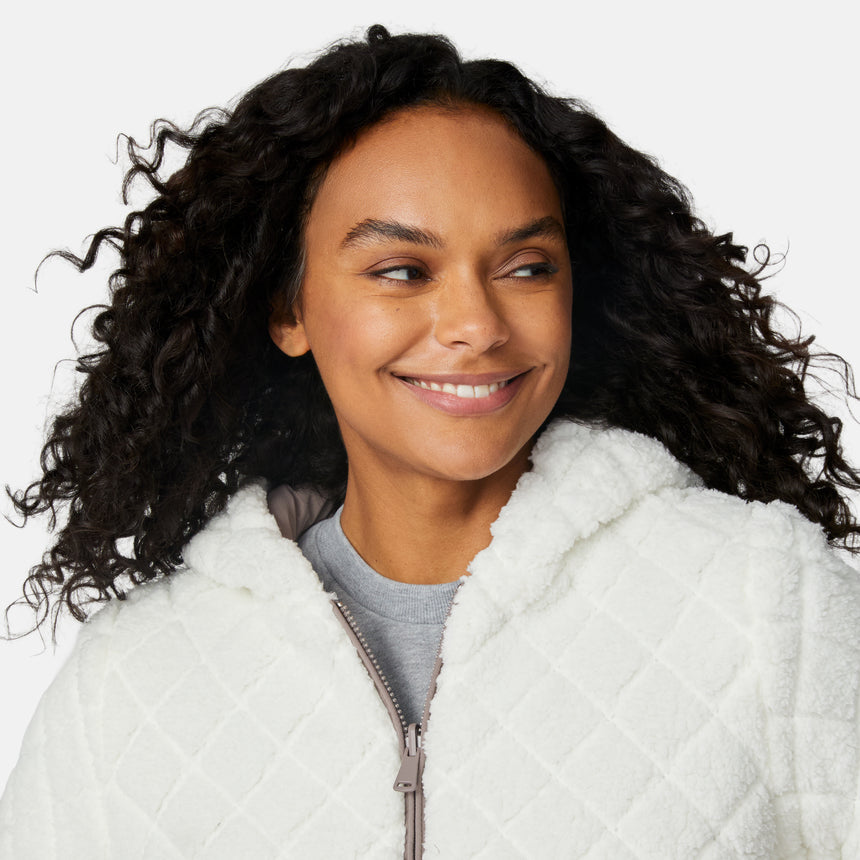 [Angelique is 5'10" wearing size S.] Light brown quilted reversible jacket with fleece-lined hood, zip front, and pockets; worn over grey shirt and blue pants.
