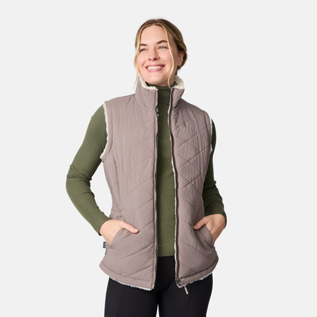 [CJ is 5'10" wearing size S.] Woman wearing a tan quilted vest over a green sweater on a white background