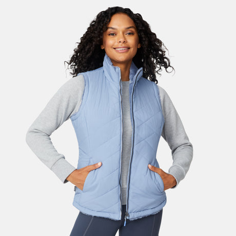 [Angelique is 5'10" wearing size S.] Woman wearing a light blue quilted vest over a gray long-sleeve shirt on a white background