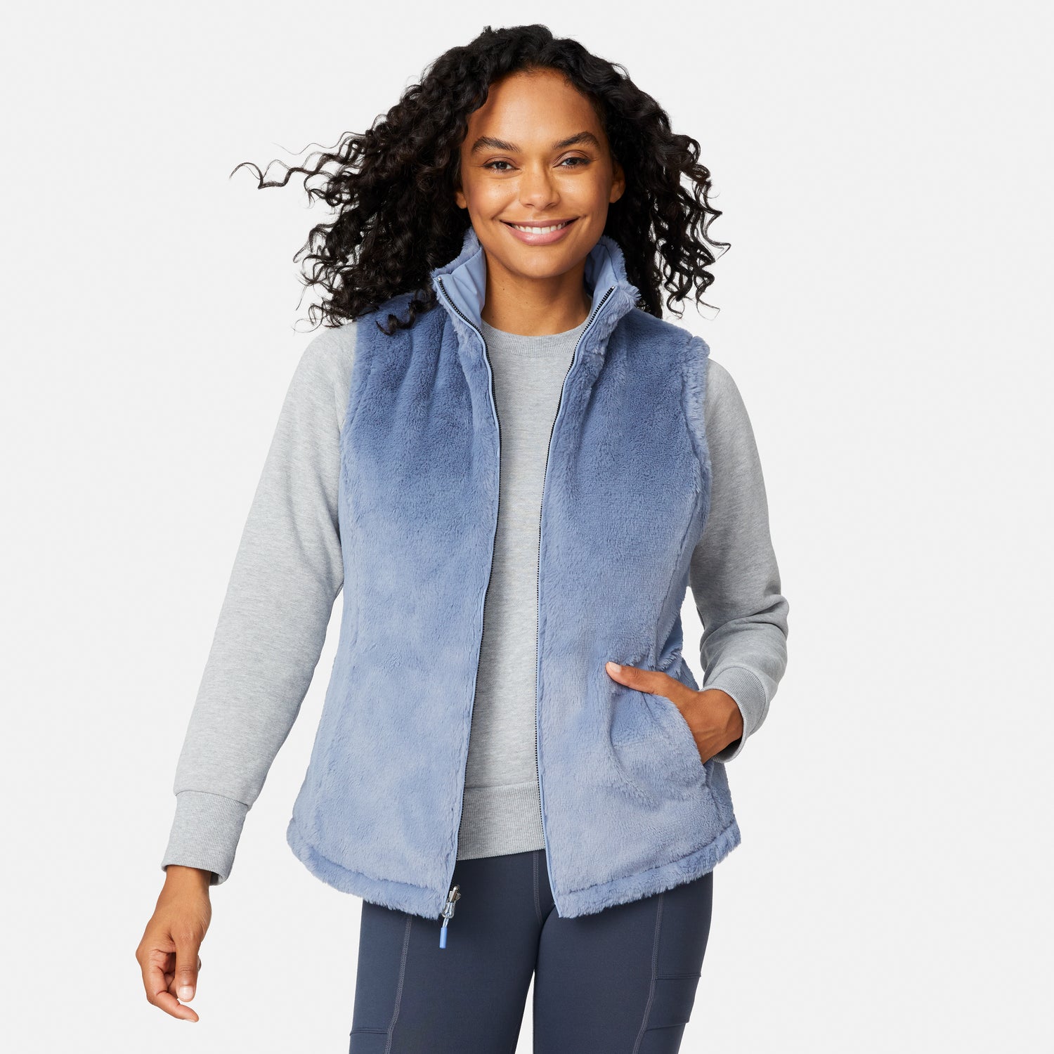 [Angelique is 5'10" wearing size S.] Woman wearing a blue fleece vest over a gray long-sleeve shirt on a white background
