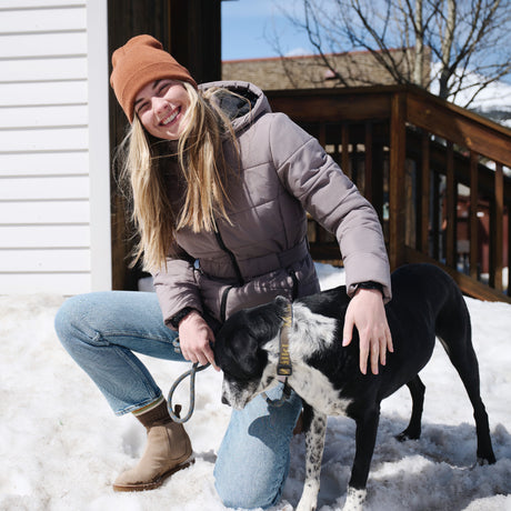 Person in winter clothing with a dog on a snowy day