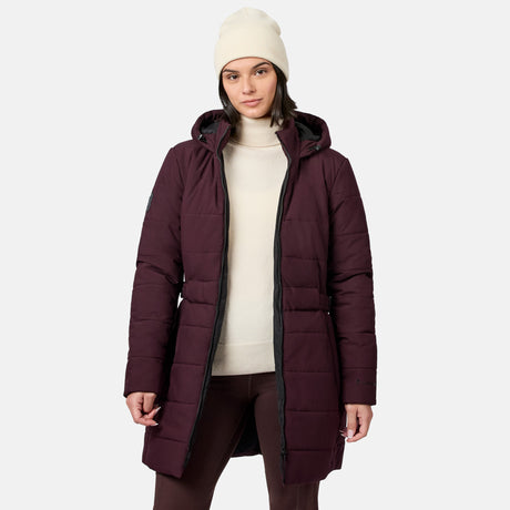 A woman wearing a dark burgundy Women’s Cirrus Quilted Long Puffer Jacket over a cream turtleneck sweater and a matching beanie.