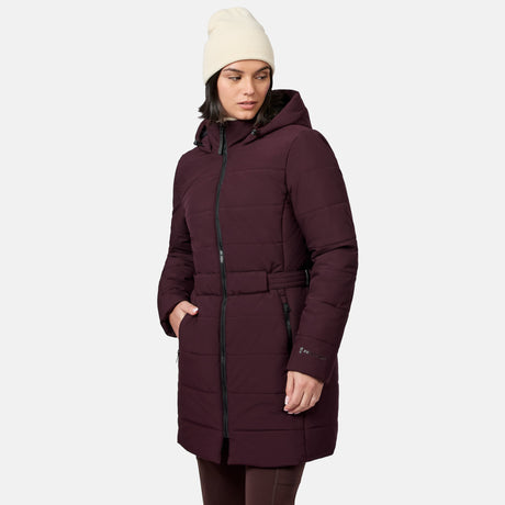 A person wearing a Jam-colored Women’s Cirrus Quilted Long Puffer Jacket, a hooded, belted, recycled polyester piece with zippered pockets.