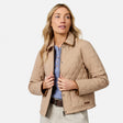 [Model is wearing size S.] A woman wearing a beige diamond-quilted jacket over a light blue knit top and khaki pants, photographed against a clean light gray studio background.