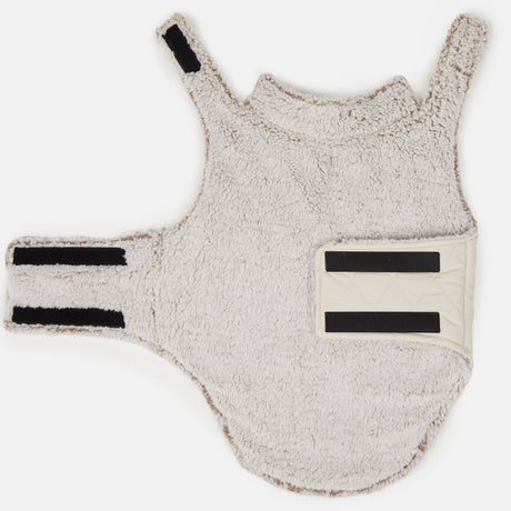 The Clearance Stratus Lite Reversible Dog Jacket is a soft, light beige fleece harness with velcro straps and a quilted cream fastener, shown flat on white—ideal as a wind-resistant jacket for breezy dog walks.